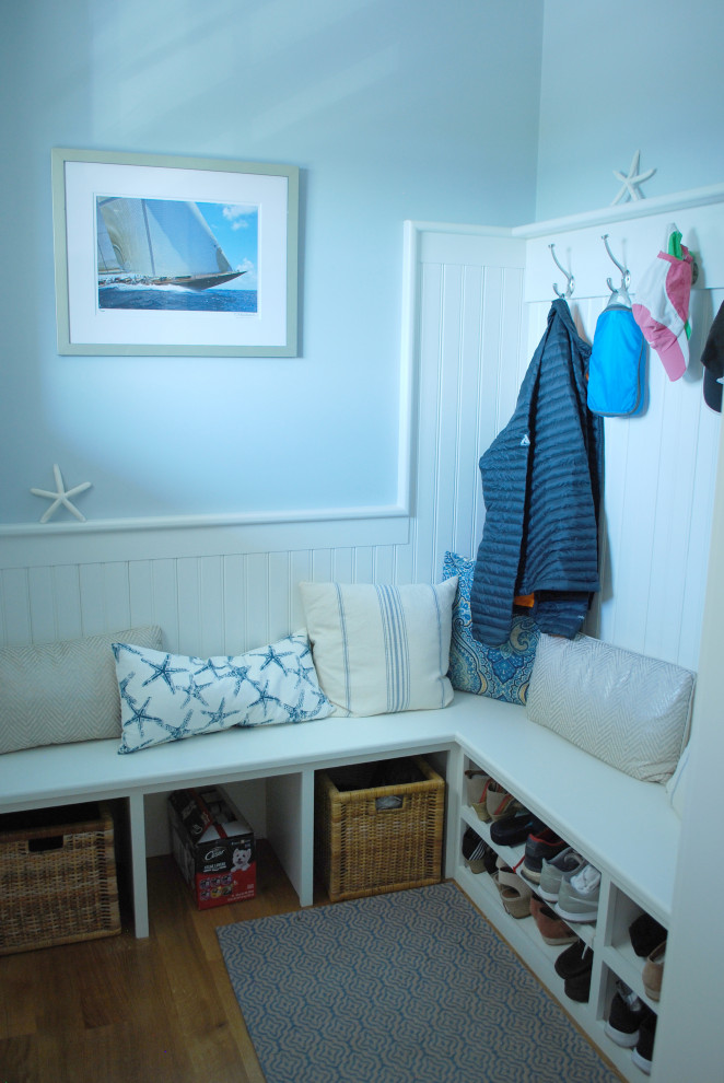 This is an example of a mid-sized beach style mudroom in Providence with blue walls, light hardwood floors and decorative wall panelling.