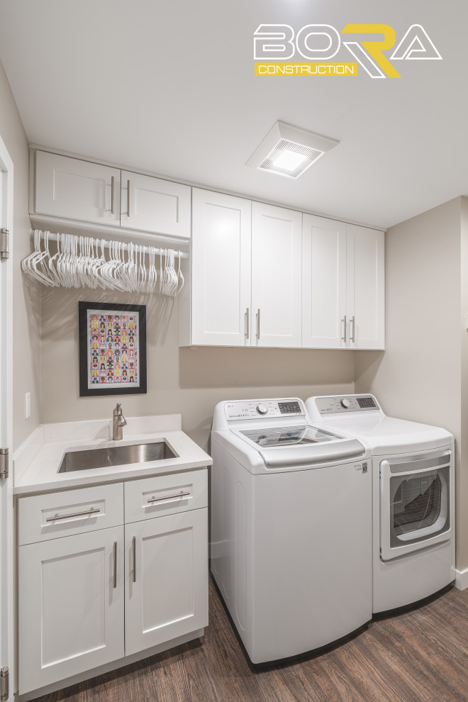 Design ideas for a small transitional single-wall laundry cupboard in Seattle with an undermount sink, shaker cabinets, white cabinets, quartz benchtops, beige walls, dark hardwood floors, a side-by-side washer and dryer, brown floor and beige benchtop.