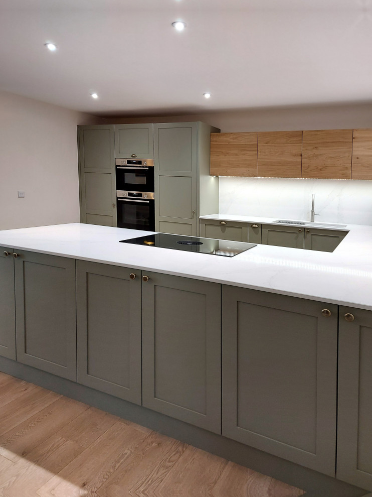 Medium sized traditional u-shaped open plan kitchen in Other with a double-bowl sink, shaker cabinets, green cabinets, quartz worktops, white splashback, engineered quartz splashback, stainless steel appliances, plywood flooring, a breakfast bar, beige floors and white worktops.