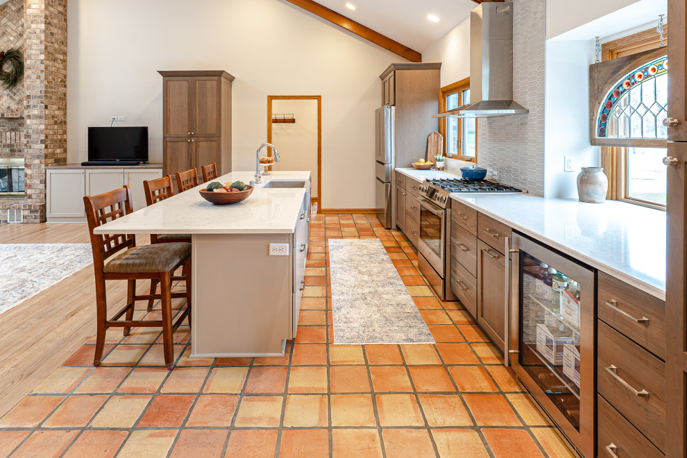 Idéer för stora vintage linjära gult kök med öppen planlösning, med en rustik diskho, skåp i shakerstil, skåp i mörkt trä, bänkskiva i kvarts, grått stänkskydd, stänkskydd i keramik, rostfria vitvaror, klinkergolv i terrakotta, en köksö och flerfärgat golv