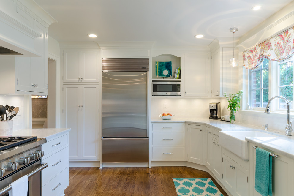 Transitional u-shaped kitchen in Richmond with a farmhouse sink, beaded inset cabinets, white cabinets, marble benchtops, white splashback, stainless steel appliances and medium hardwood floors.