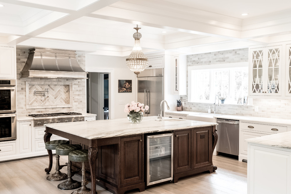 Inspiration for a large traditional u-shaped eat-in kitchen in Indianapolis with a farmhouse sink, raised-panel cabinets, white cabinets, marble benchtops, ceramic splashback, stainless steel appliances, light hardwood floors, with island and grey floor.