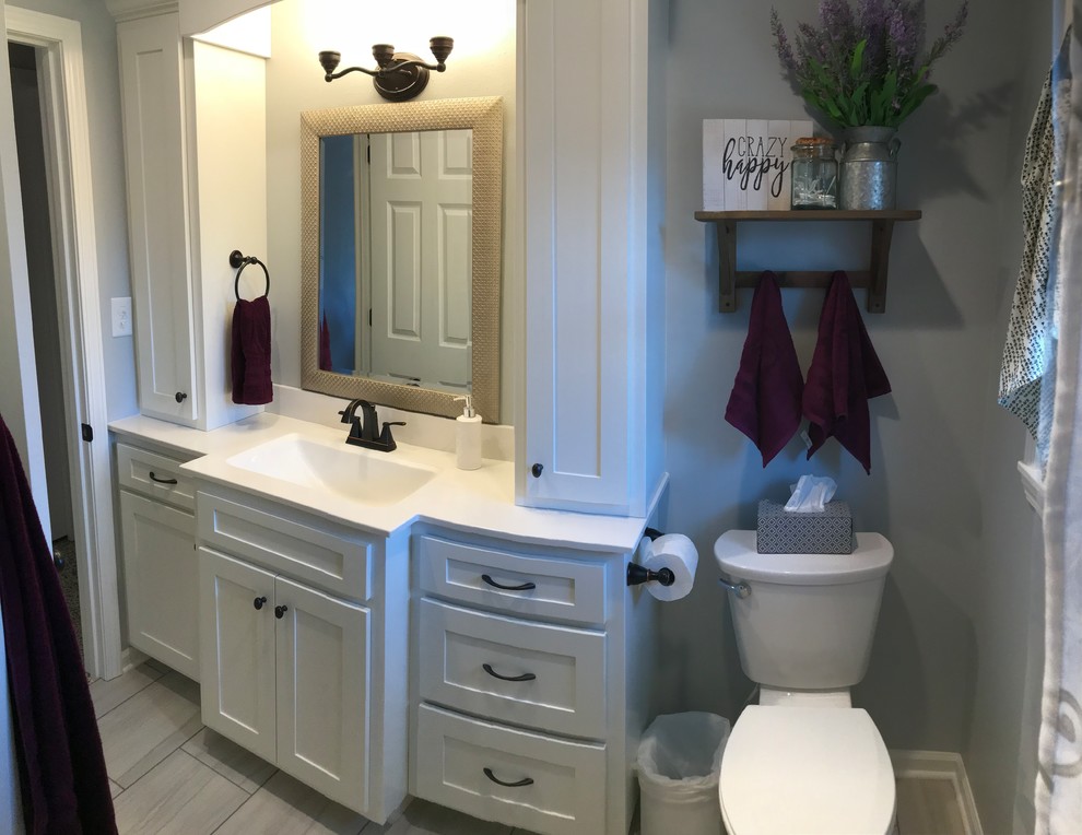 Inspiration for a mid-sized transitional tub/shower combo remodel with recessed-panel cabinets, white cabinets, a one-piece toilet, a drop-in sink and white countertops