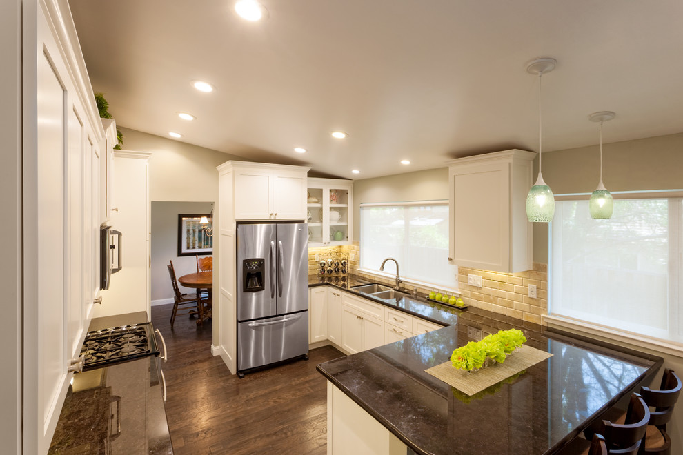 Design ideas for a traditional u-shaped eat-in kitchen in San Francisco with an undermount sink, raised-panel cabinets, white cabinets, granite benchtops, beige splashback, stone tile splashback and stainless steel appliances.