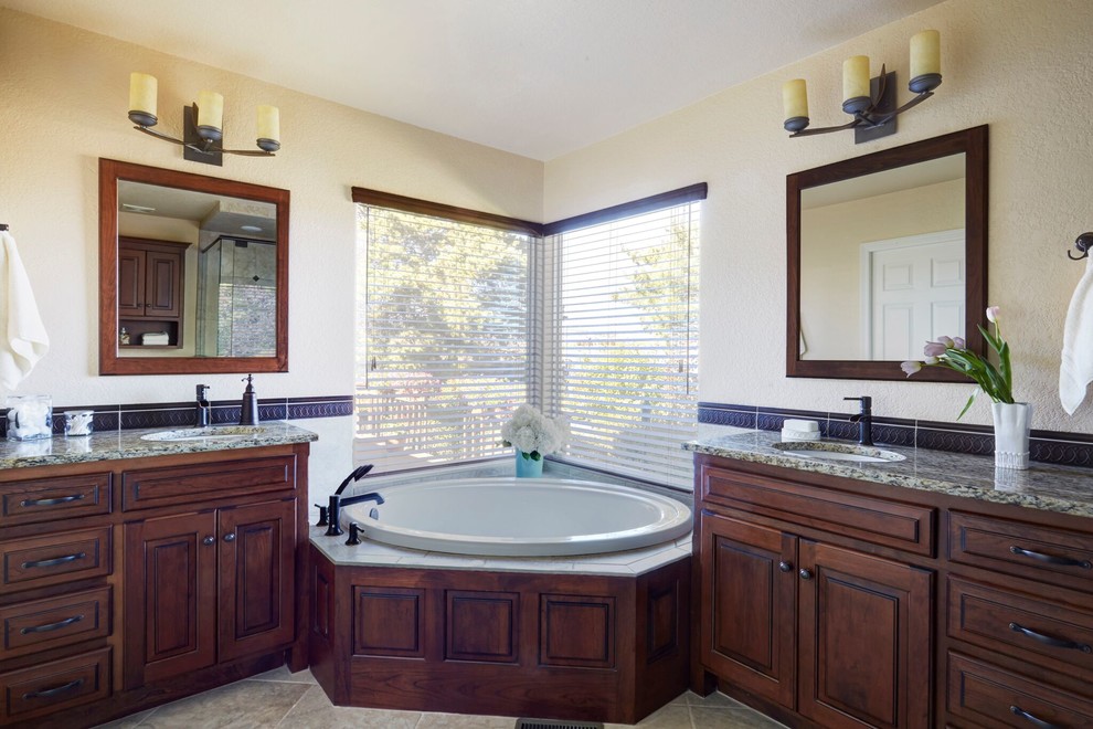 Inspiration for a large traditional master bathroom in Denver with raised-panel cabinets, dark wood cabinets, a drop-in tub, an alcove shower, a one-piece toilet, beige tile, ceramic tile, beige walls, travertine floors, an undermount sink and granite benchtops.