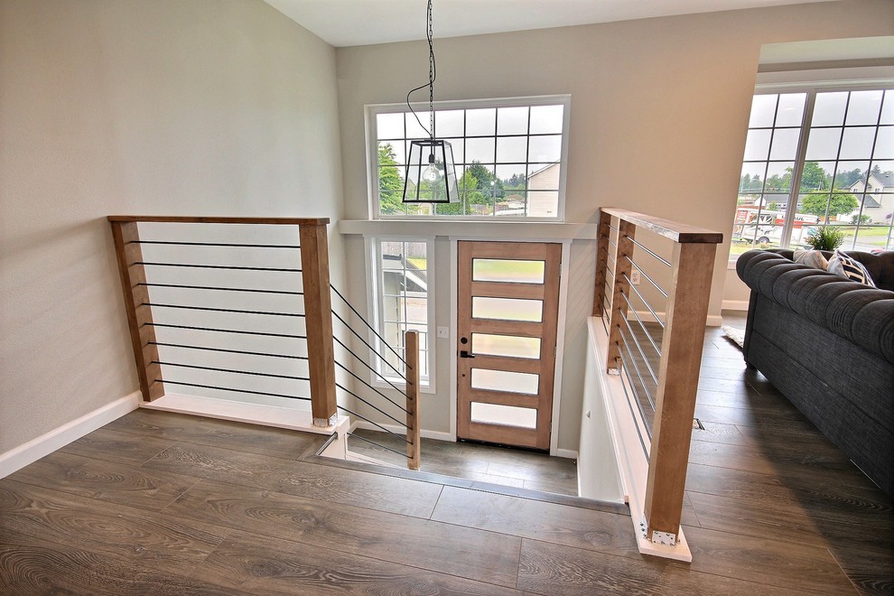 Photo of a mid-sized country foyer in Seattle with grey walls, laminate floors, a single front door, a medium wood front door and grey floor.