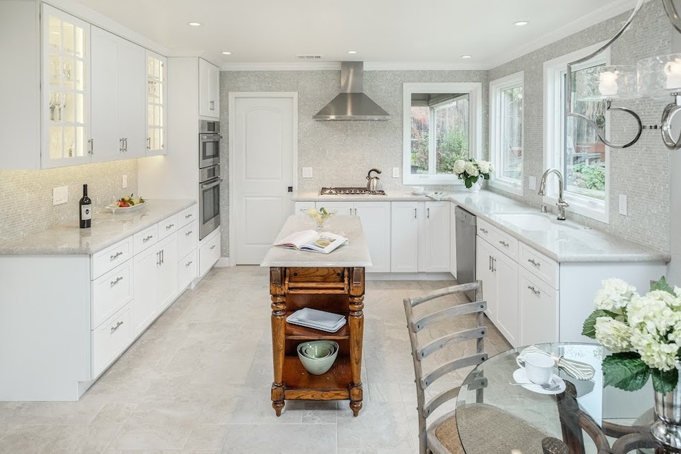 Large transitional u-shaped limestone floor and gray floor eat-in kitchen photo with an undermount sink, shaker cabinets, white cabinets, marble countertops, metallic backsplash, mosaic tile backsplash, stainless steel appliances and an island
