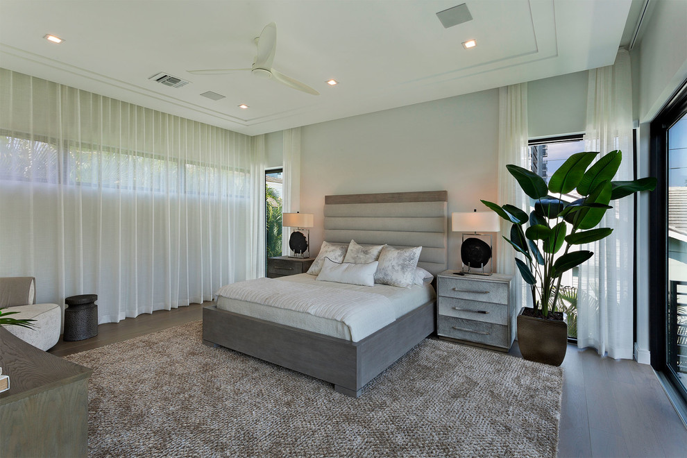 Photo of a mid-sized modern master bedroom in Miami with beige walls, medium hardwood floors, no fireplace and brown floor.