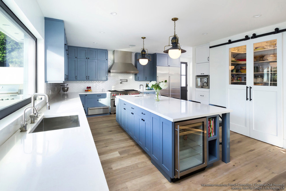 Design ideas for a scandinavian eat-in kitchen in Los Angeles with shaker cabinets, blue cabinets, light hardwood floors and with island.