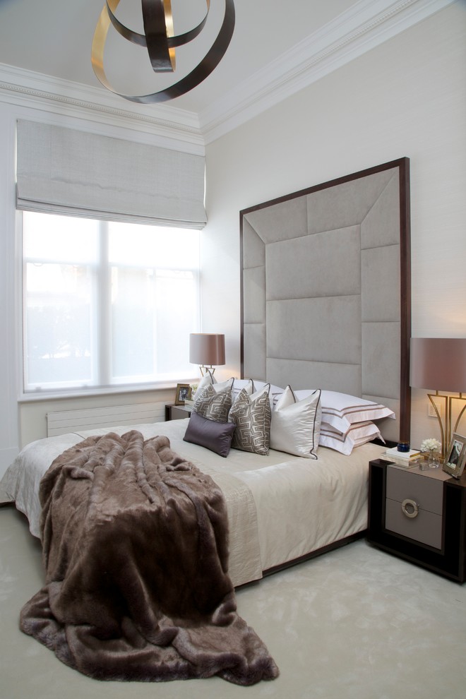 This is an example of a transitional master bedroom in London with beige walls and carpet.