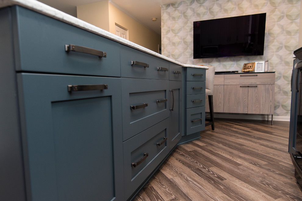 Mid-sized transitional l-shaped eat-in kitchen in Baltimore with a single-bowl sink, shaker cabinets, grey cabinets, quartz benchtops, grey splashback, subway tile splashback, stainless steel appliances, with island, brown floor and white benchtop.