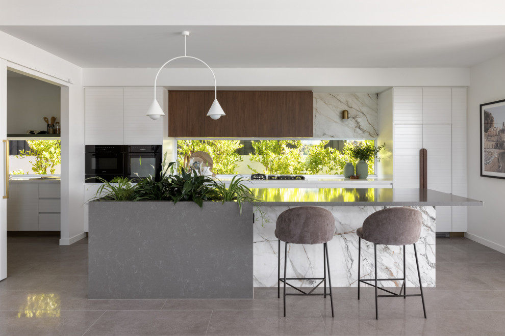 Inspiration for a large modern galley kitchen pantry in Brisbane with a drop-in sink, white cabinets, marble benchtops, black appliances, porcelain floors, with island, grey floor and grey benchtop.