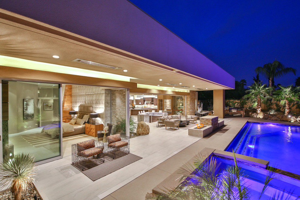This is an example of an expansive contemporary backyard patio in Los Angeles with a fire feature, tile and a roof extension.