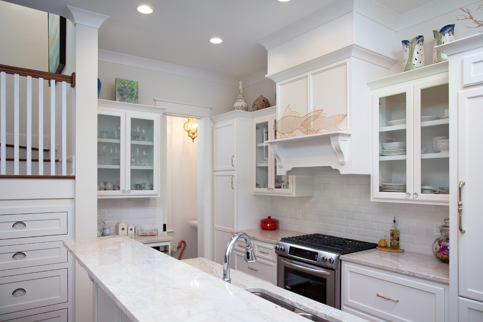 Inspiration for a small beach style galley kitchen in Charleston with a double-bowl sink, recessed-panel cabinets, white cabinets, granite benchtops, white splashback, subway tile splashback, stainless steel appliances, medium hardwood floors and a peninsula.