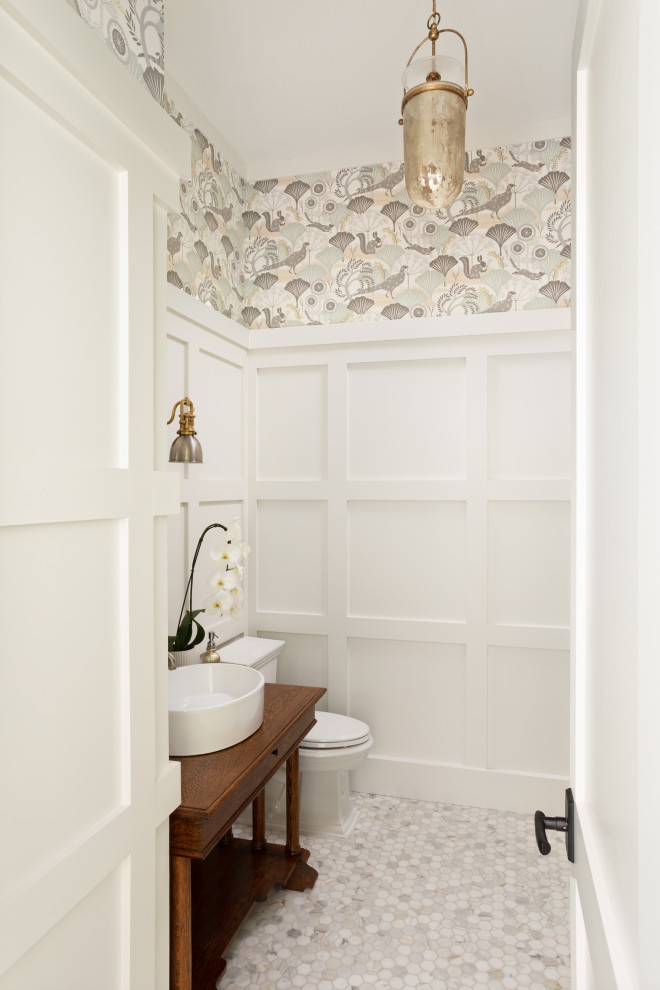 This is an example of a beach style powder room in Tampa with medium wood cabinets, white walls, pebble tile floors, wood benchtops, grey floor, brown benchtops, a freestanding vanity and decorative wall panelling.