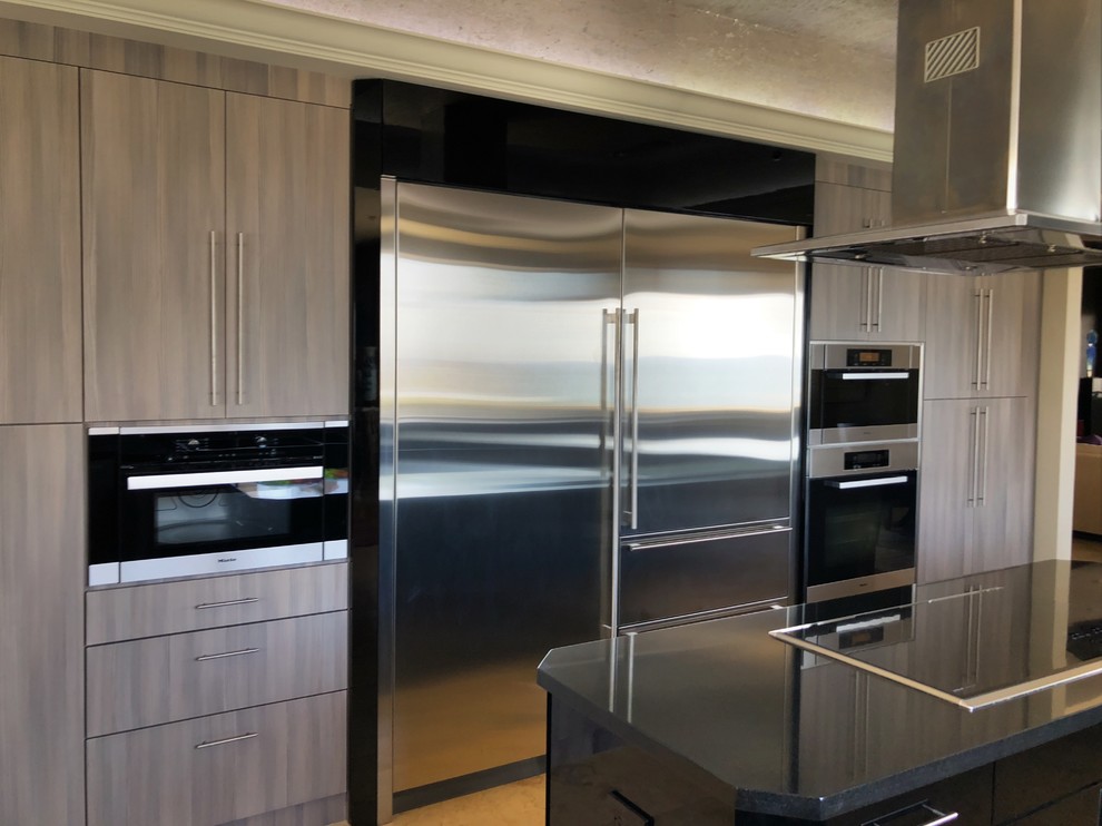 Large contemporary u-shaped kitchen pantry in Miami with a farmhouse sink, flat-panel cabinets, grey cabinets, granite benchtops, black splashback, with island, black benchtop, ceramic floors and beige floor.