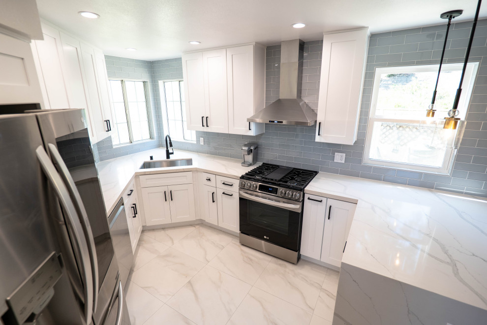 Enclosed kitchen - mid-sized modern u-shaped marble floor and white floor enclosed kitchen idea in Los Angeles with a drop-in sink, raised-panel cabinets, white cabinets, granite countertops, blue backsplash, subway tile backsplash, stainless steel appliances, no island and white countertops