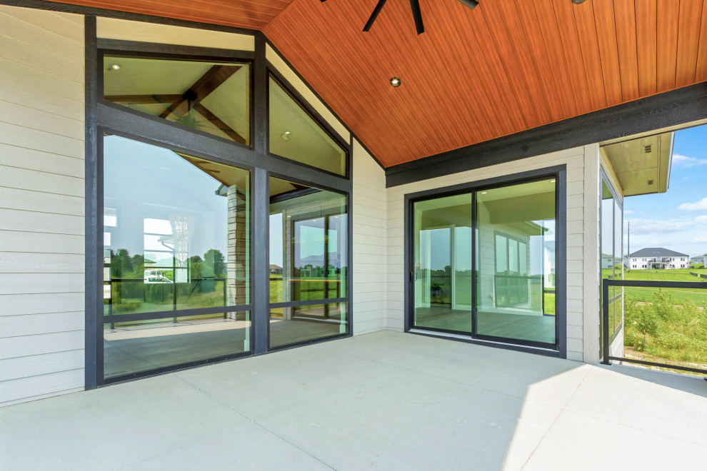 Inspiration for a large transitional backyard ground level glass railing deck remodel with a roof extension