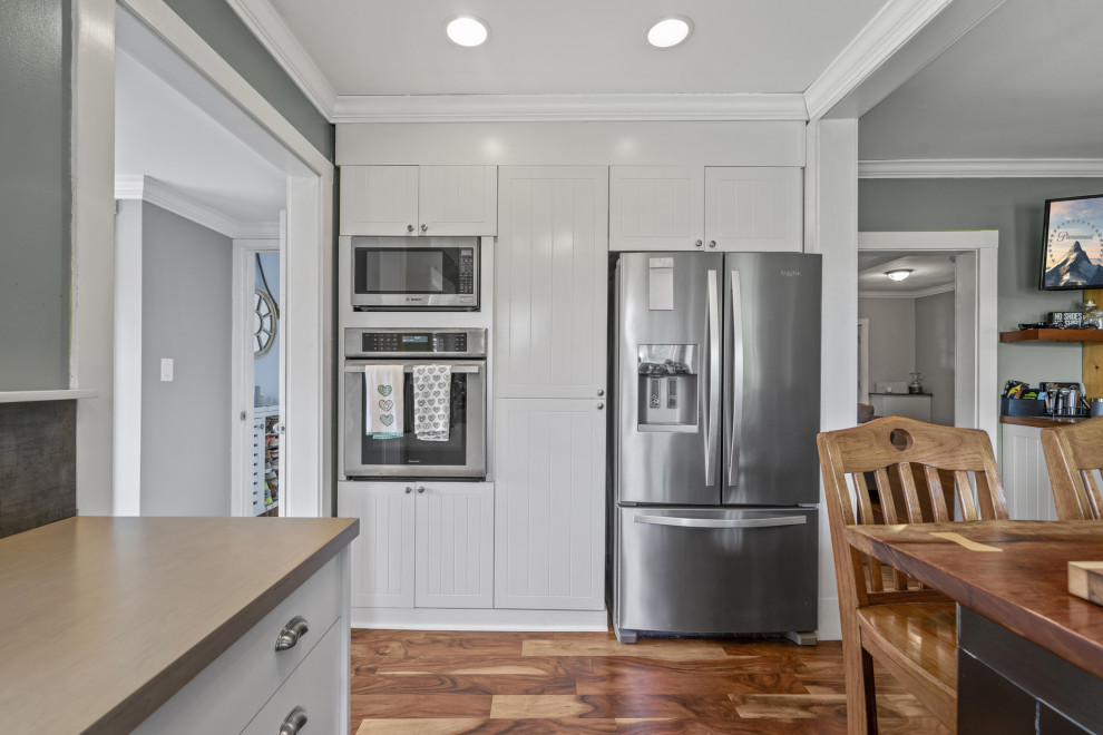 This is an example of an expansive single-wall eat-in kitchen in DC Metro with a farmhouse sink, stainless steel appliances, bamboo floors and with island.