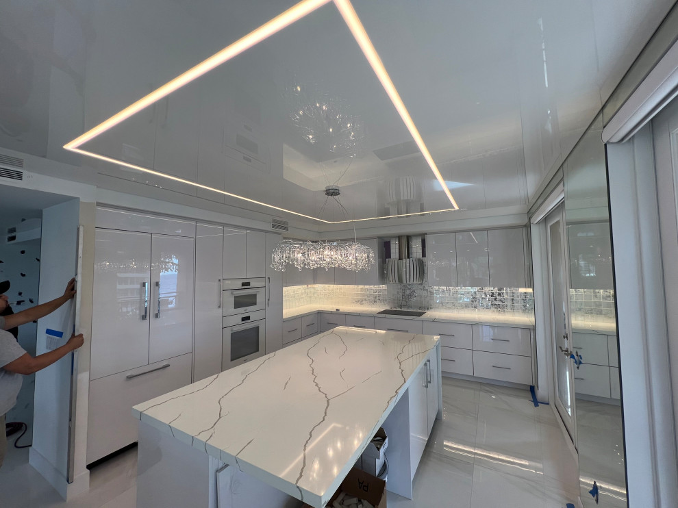 Photo of a medium sized galley enclosed kitchen in Miami with flat-panel cabinets, white cabinets, marble worktops, white splashback, an island and a wallpapered ceiling.