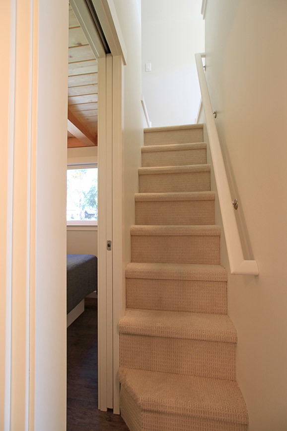 Small arts and crafts carpeted straight staircase in Seattle with carpet risers.