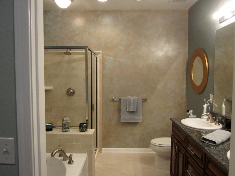 Photo of a transitional 3/4 bathroom in New York with raised-panel cabinets, dark wood cabinets, a drop-in tub, a corner shower, a two-piece toilet, ceramic tile, beige walls, ceramic floors, a drop-in sink, granite benchtops, beige floor and a hinged shower door.