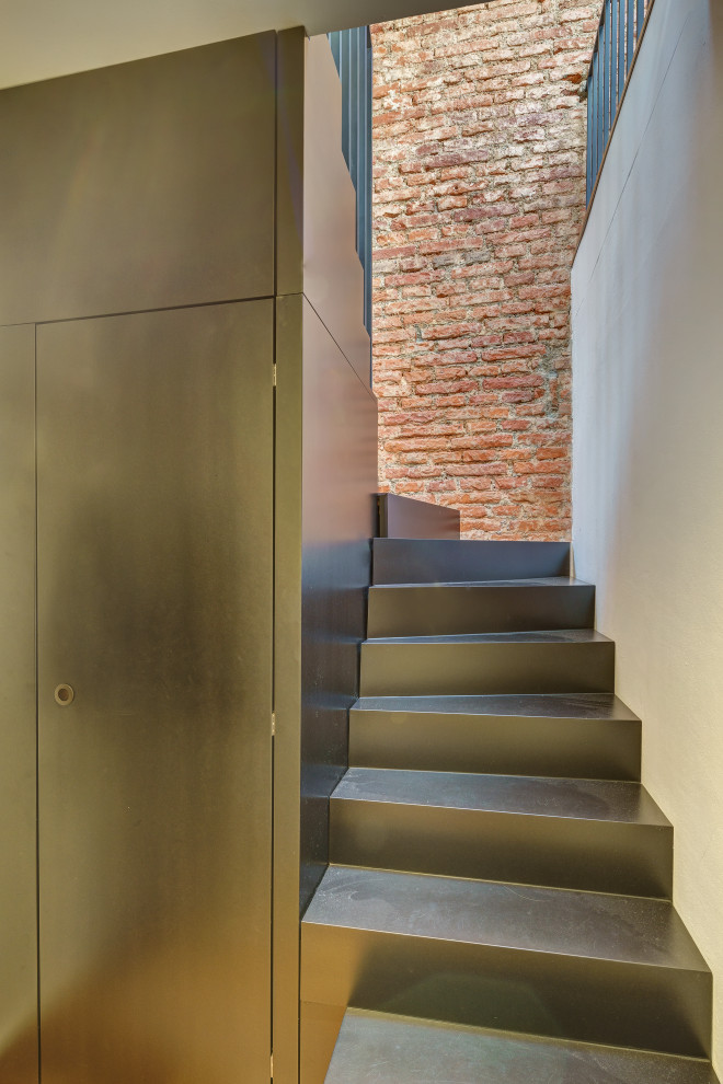 Réalisation d'un petit escalier courbe bohème avec des marches en bois, des contremarches en bois, un garde-corps en métal et un mur en parement de brique.