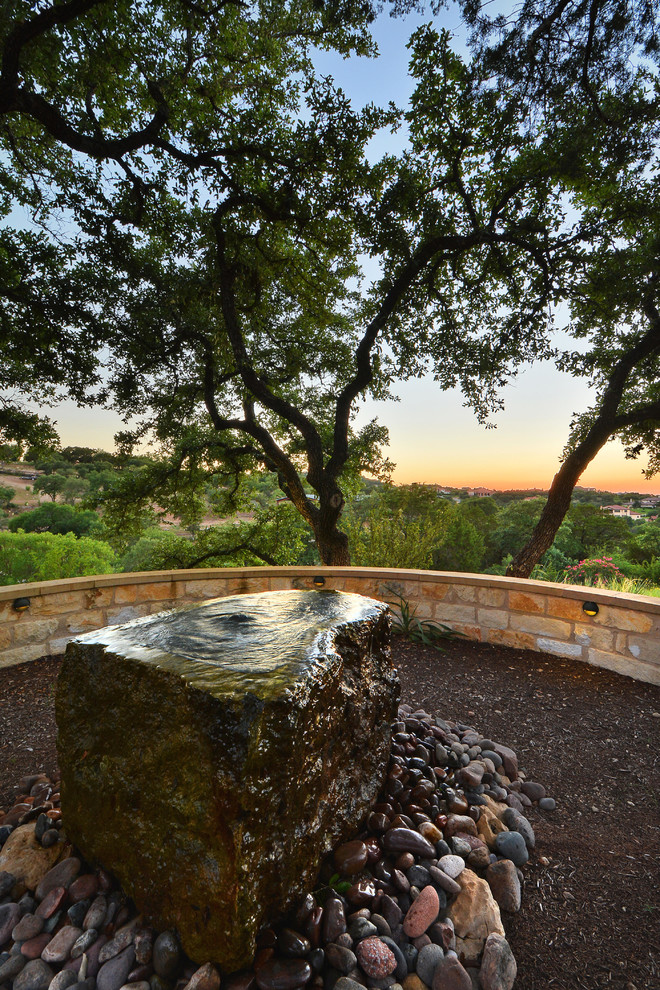 Inspiration for a large country sloped garden in Austin with a water feature and brick pavers.