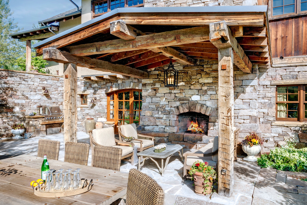 Design ideas for a large country backyard patio in Other with natural stone pavers, a pergola and with fireplace.