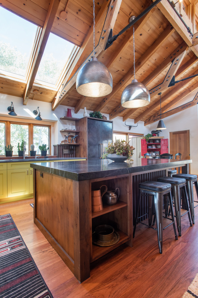 Eat-in kitchen - large rustic l-shaped medium tone wood floor and exposed beam eat-in kitchen idea in Denver with shaker cabinets, green cabinets, soapstone countertops, metallic backsplash, two islands and black countertops
