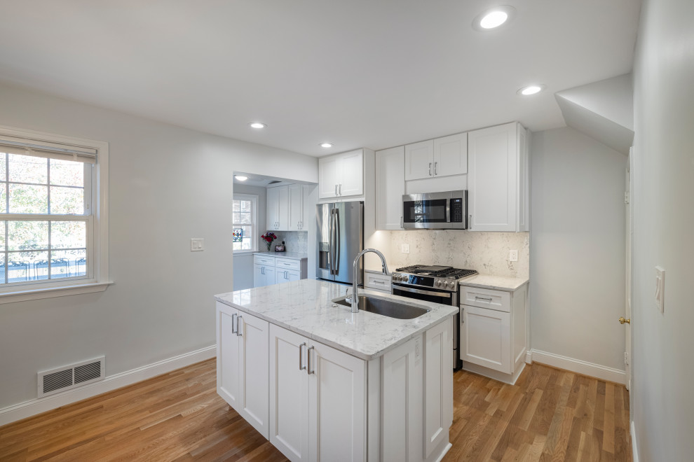 Medium sized contemporary kitchen in DC Metro with a submerged sink, raised-panel cabinets, white cabinets, engineered stone countertops, multi-coloured splashback, engineered quartz splashback, stainless steel appliances, medium hardwood flooring, an island, grey floors and multicoloured worktops.