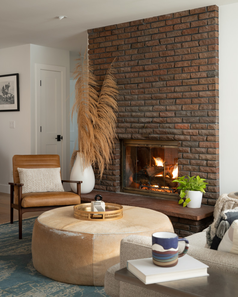 Minimalist open concept light wood floor living room photo in Denver with white walls, a wood stove and a brick fireplace