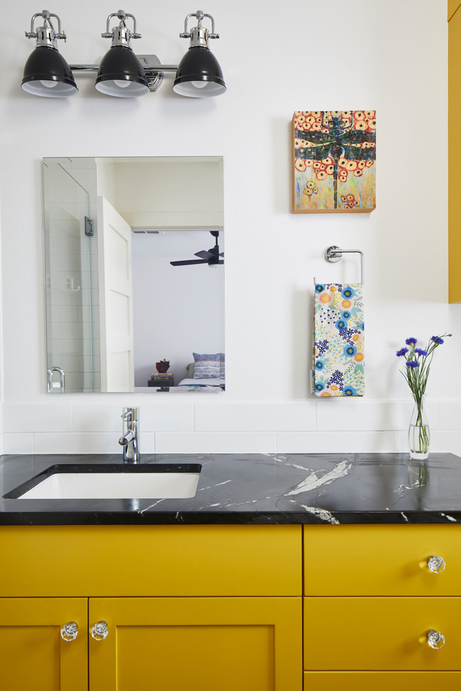 Small eclectic master wet room bathroom in Austin with shaker cabinets, yellow cabinets, a one-piece toilet, white tile, ceramic tile, white walls, ceramic floors, an undermount sink, soapstone benchtops, white floor, a hinged shower door and black benchtops.
