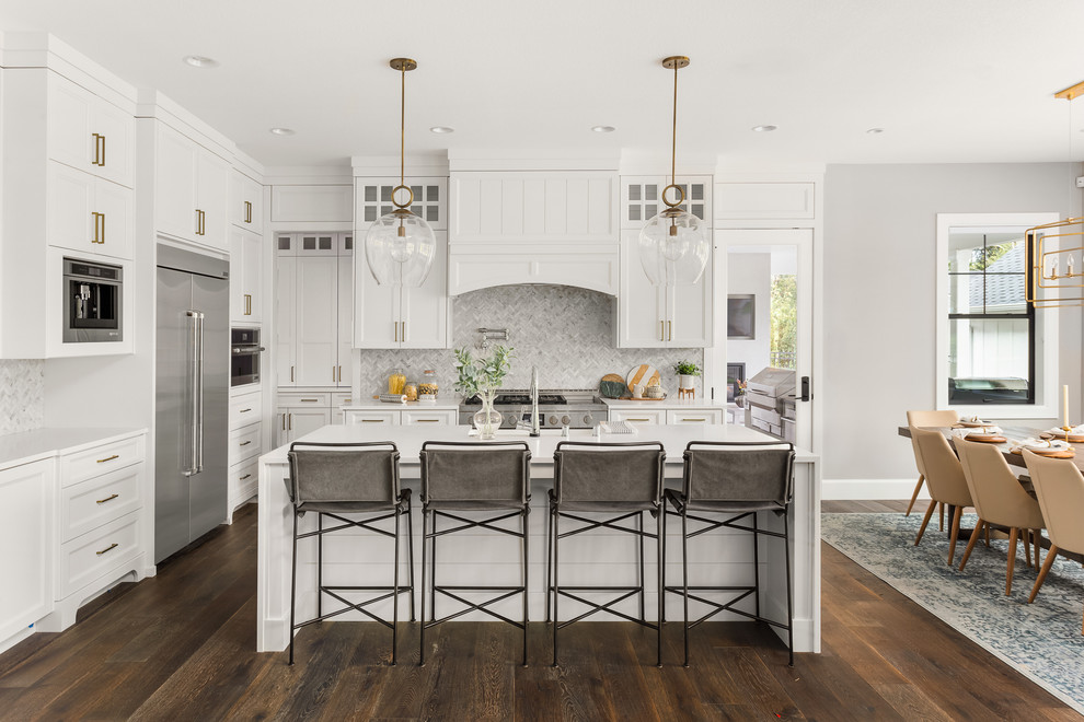 Example of a transitional l-shaped dark wood floor and brown floor eat-in kitchen design in Portland with recessed-panel cabinets, white cabinets, gray backsplash, mosaic tile backsplash, stainless steel appliances, an island and white countertops