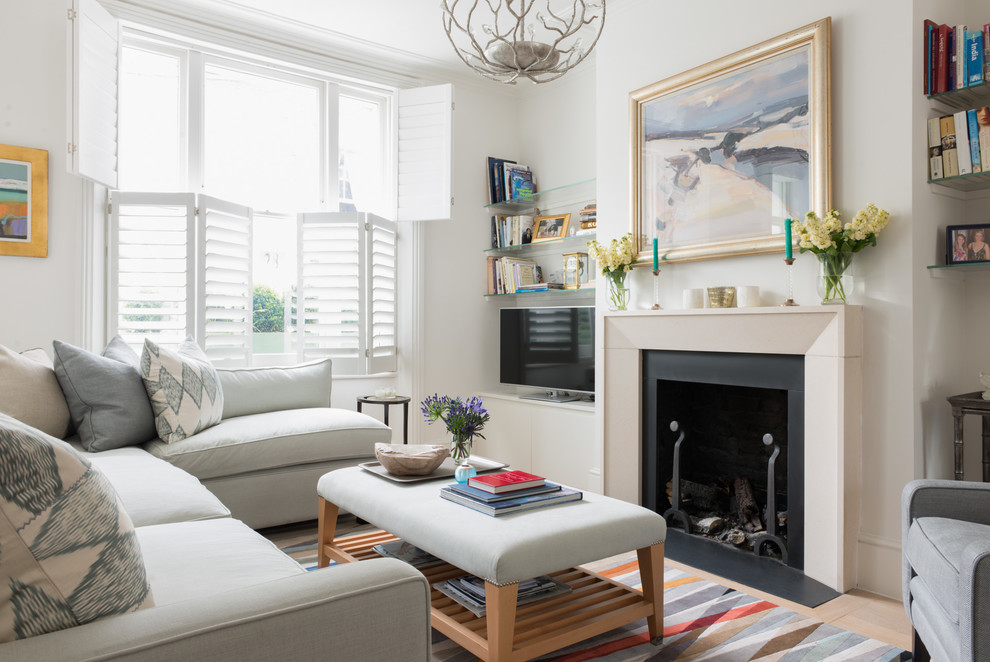 This is an example of a mid-sized contemporary open concept living room in London with white walls, light hardwood floors, a standard fireplace, a stone fireplace surround and a freestanding tv.