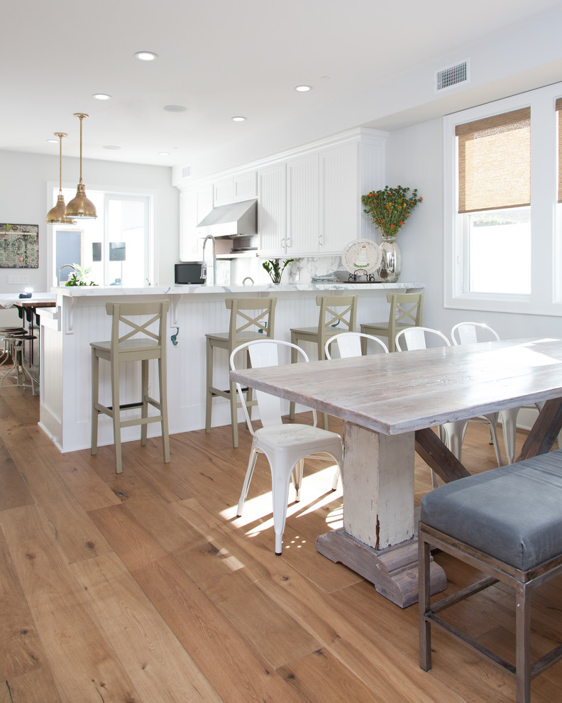 This is an example of a beach style eat-in kitchen in Orange County with white cabinets.