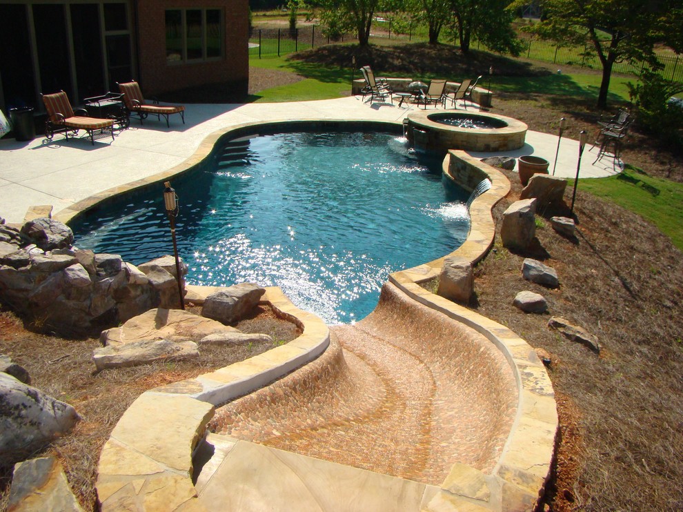 Large traditional backyard custom-shaped pool in Atlanta with a water slide and natural stone pavers.