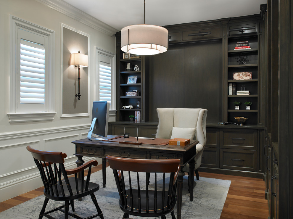 This is an example of a traditional study room in Miami with white walls, medium hardwood floors, no fireplace, a freestanding desk and brown floor.
