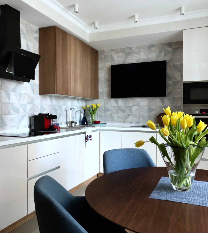 Photo of a mid-sized contemporary l-shaped eat-in kitchen in Moscow with flat-panel cabinets, white cabinets, grey splashback, stainless steel appliances, grey floor and white benchtop.