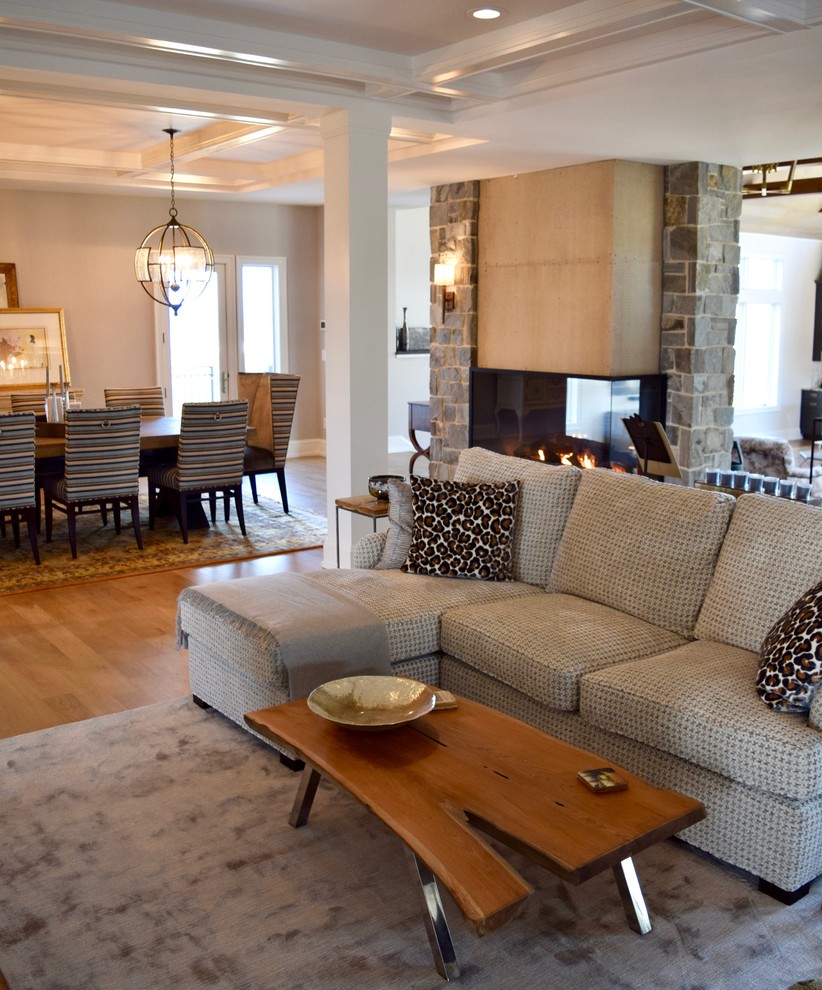 Mid-sized transitional open concept living room in Other with grey walls, light hardwood floors, a two-sided fireplace, a stone fireplace surround and beige floor.