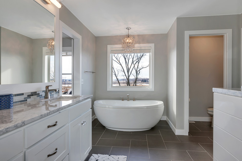 Design ideas for a mid-sized country master bathroom in Minneapolis with shaker cabinets, white cabinets, a freestanding tub, a one-piece toilet, grey walls, ceramic floors, an undermount sink, granite benchtops, grey floor, a double shower and a shower curtain.