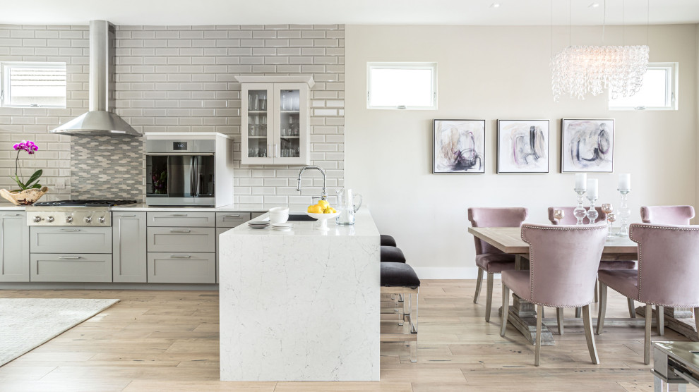 Aménagement d'une petite salle à manger ouverte sur la cuisine contemporaine avec un mur gris, parquet clair, une cheminée standard, un manteau de cheminée en pierre de parement et un sol beige.