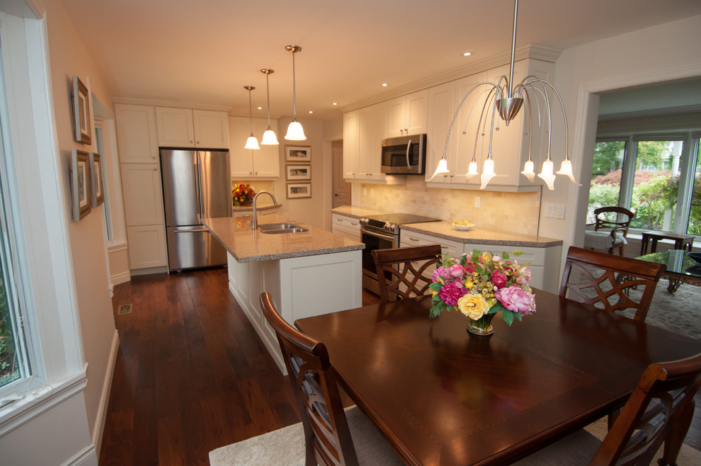 Inspiration for a mid-sized transitional l-shaped dark wood floor eat-in kitchen remodel in Toronto with a double-bowl sink, shaker cabinets, white cabinets, granite countertops, beige backsplash, ceramic backsplash, stainless steel appliances and an island