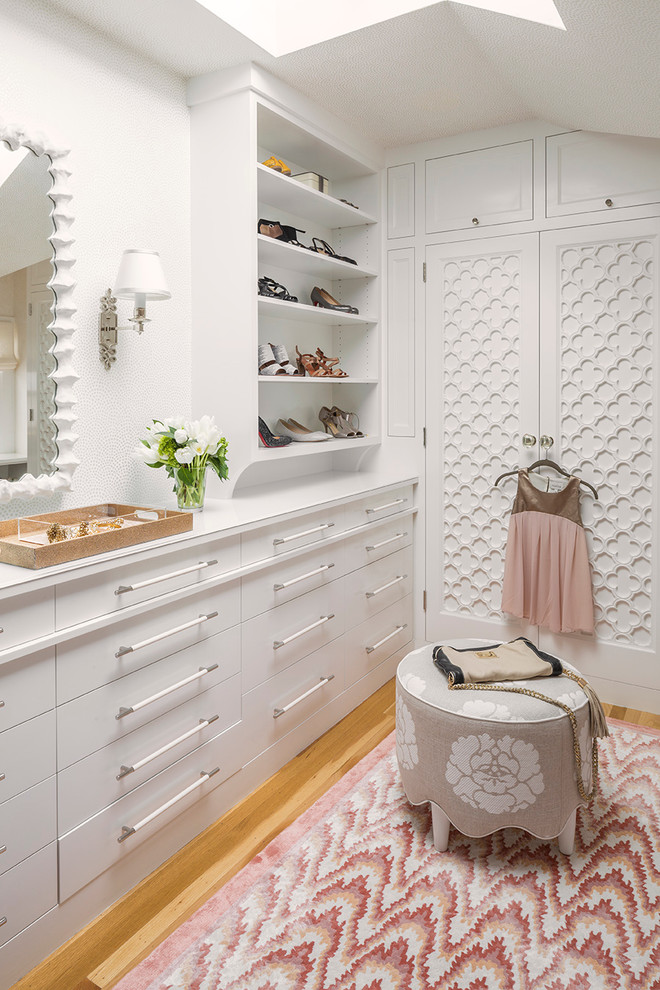 Photo of a transitional women's dressing room in Seattle with flat-panel cabinets, white cabinets, light hardwood floors and beige floor.