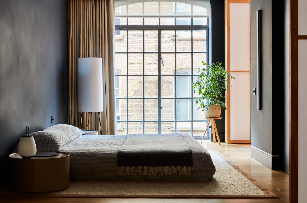 Kleines Modernes Hauptschlafzimmer mit schwarzer Wandfarbe und braunem Holzboden in London