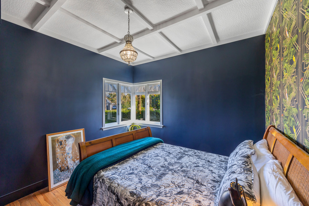 Photo of a mid-sized eclectic master bedroom in Auckland with blue walls, medium hardwood floors, brown floor and coffered.