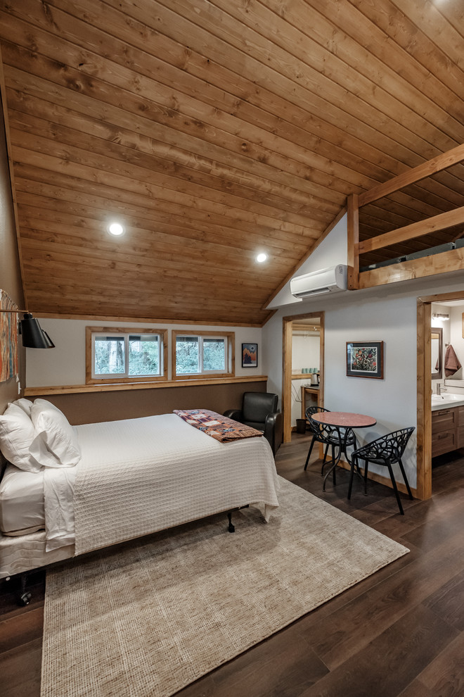 Photo of a country bedroom in Portland with white walls, dark hardwood floors and brown floor.
