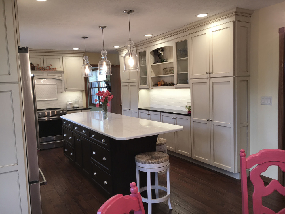 Large transitional medium tone wood floor and brown floor eat-in kitchen photo with an undermount sink, flat-panel cabinets, white cabinets, granite countertops, white backsplash, porcelain backsplash, stainless steel appliances and an island