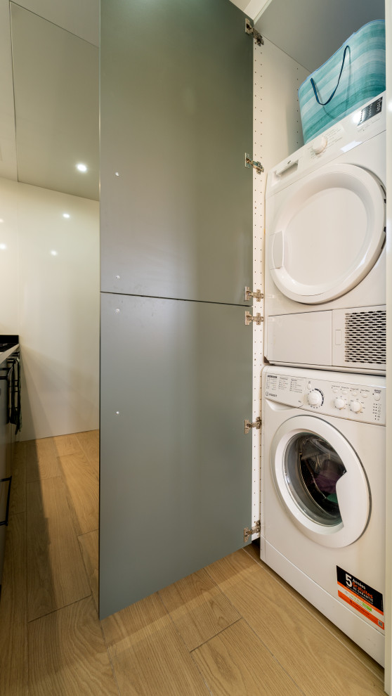 Foto på en mellanstor funkis svarta parallell tvättstuga, med en undermonterad diskho, släta luckor, grå skåp, granitbänkskiva, glaspanel som stänkskydd och beiget golv
