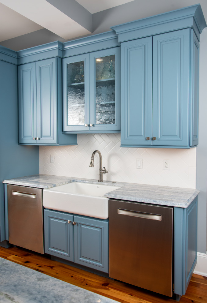 Inspiration for a large traditional galley kitchen in New York with a farmhouse sink, raised-panel cabinets, blue cabinets, marble benchtops, white splashback, subway tile splashback, stainless steel appliances, medium hardwood floors, with island, multi-coloured floor and multi-coloured benchtop.